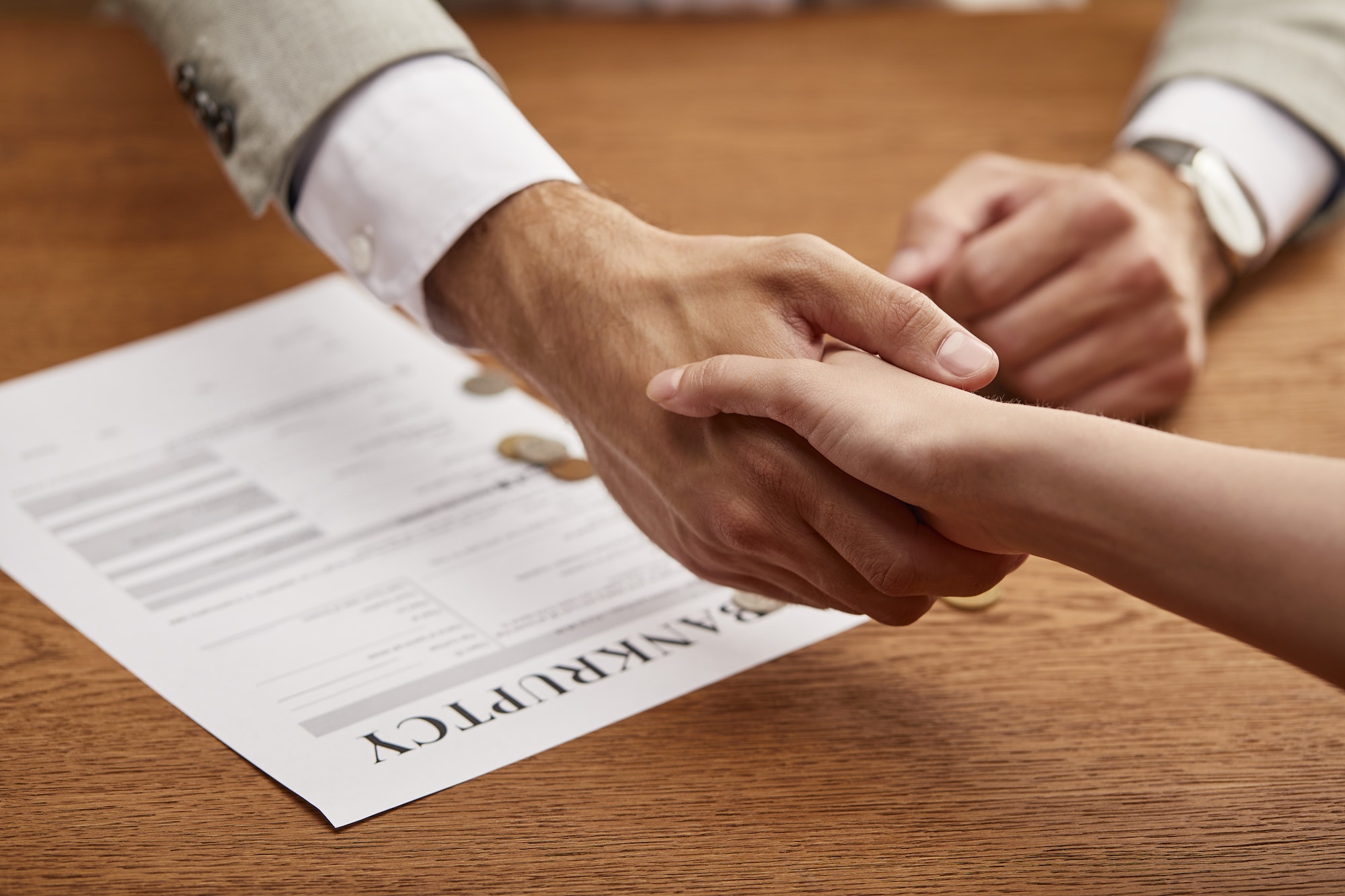 partial view of man and woman shaking hands near bankruptcy form